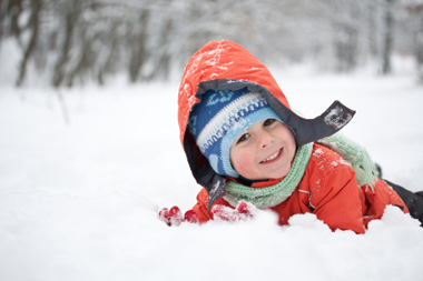 Boy smiling while playing in the snow in Big Sky Montana